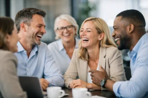 7 fordele ved at grine mere sammen. Ai billede af 5 kolleger der griner sammen.